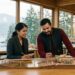 Two skilled engineering and finance professionals examining an architectural bridge scale model inside a British Columbia mass-timber studio overlooking coastal mountains